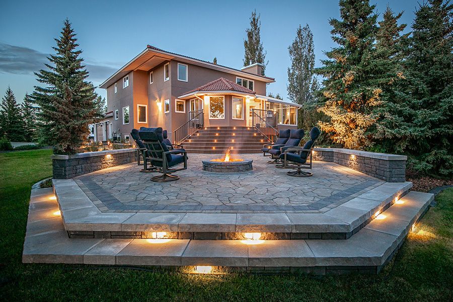 a stone patio with lights and a fire pit sitting area