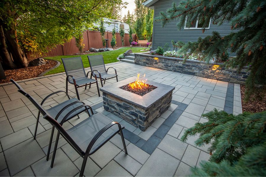a stone patio with a fire pit and a landscaped yard